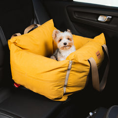 Bolsa de Transporte Cangú Explora Amarelo Solar no banco do carro, com cachorro de pequeno porte olhando para fora