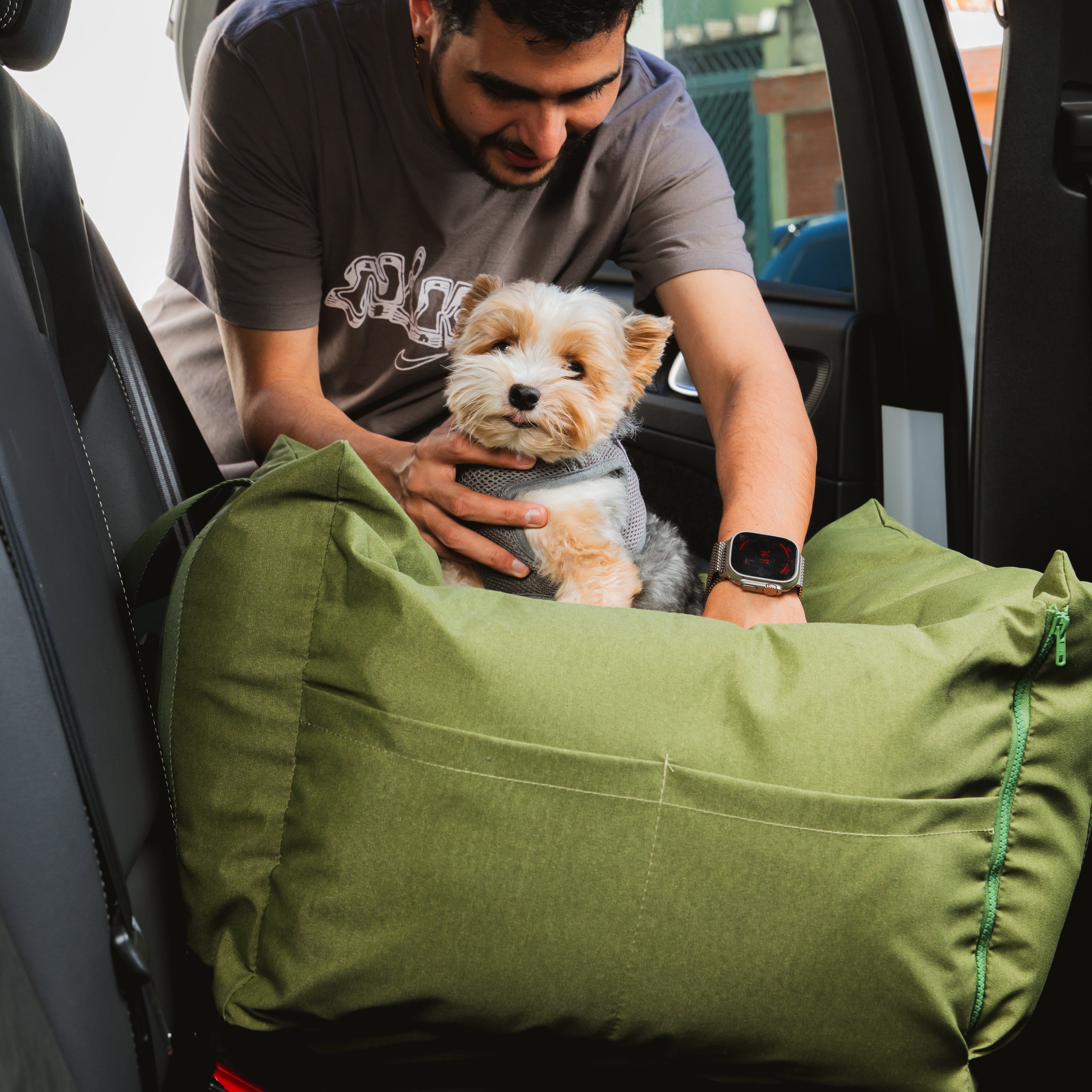 Bolsa de Transporte Cangú Explora Verde Bosque no banco do carro enquanto o tutor acomoda o cachorro dentro dela